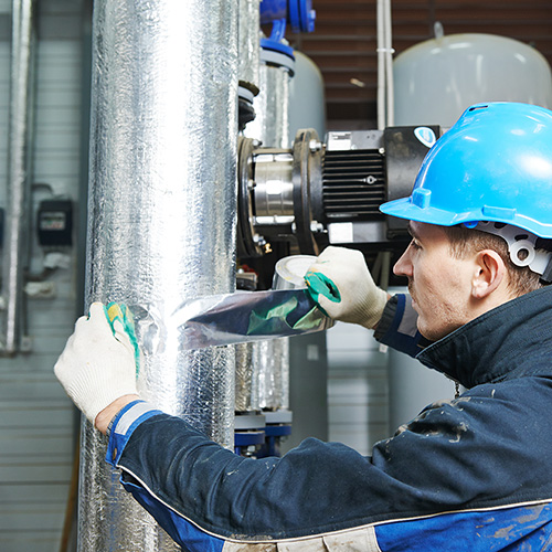 Contractor putting foil tape round pipe work insulation