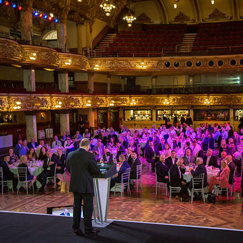 Tica Awards Luncheon Presenter speaking on stage to a large audience